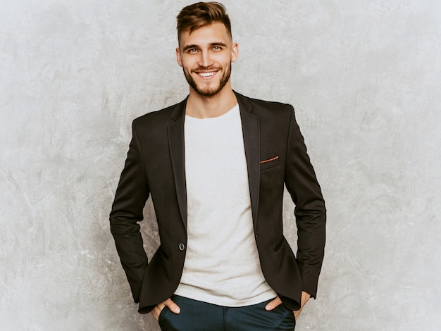 Retrato do modelo de empresário de hipster sorridente bonito vestindo terno preto casual.