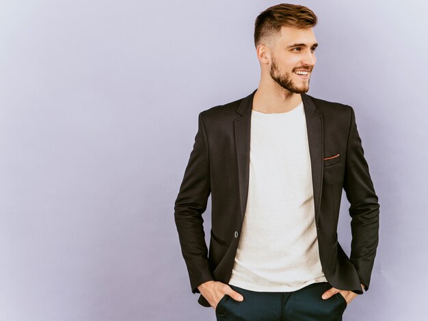 Retrato do modelo de empresário de hipster sorridente bonito vestindo terno preto casual.