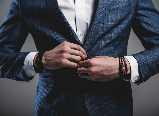 Foto grátis retrato do modelo de empresário de moda hipster elegante bonito vestido com elegante terno azul em óculos de sol posando em cinza