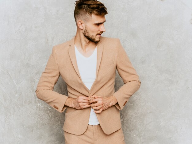 Retrato do modelo de empresário moderno sério bonito hipster vestindo terno bege casual.
