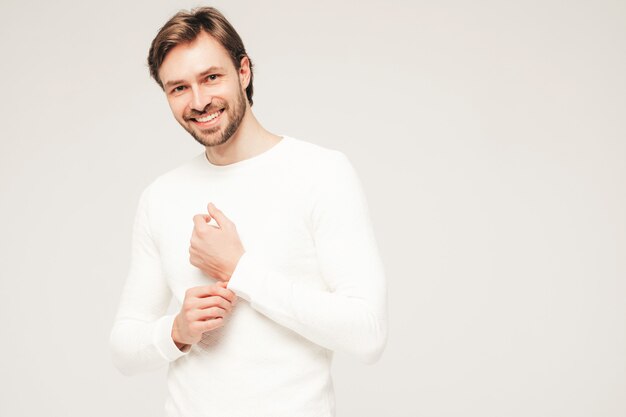 Retrato do modelo de empresário sexual lumbersexual, sorridente, bonito, vestindo calça e suéter branco casual