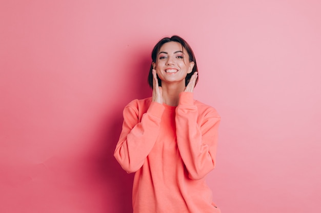 Retrato do modelo de mulher morena bonita sorridente bonita com roupas casuais de suéter pêssego com maquiagem brilhante e lábios rosados isolados