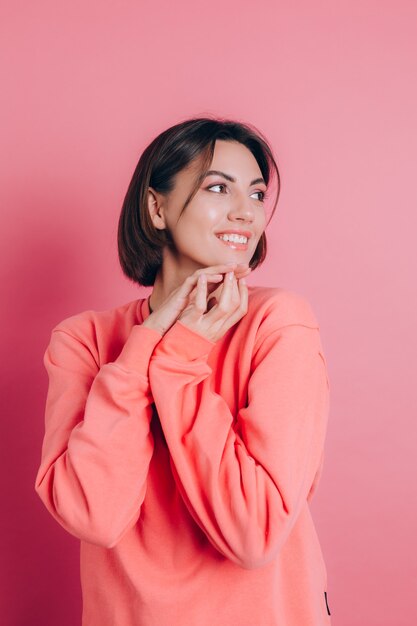 Retrato do modelo de mulher morena bonita sorridente bonita com roupas casuais de suéter pêssego com maquiagem brilhante e lábios rosados isolados