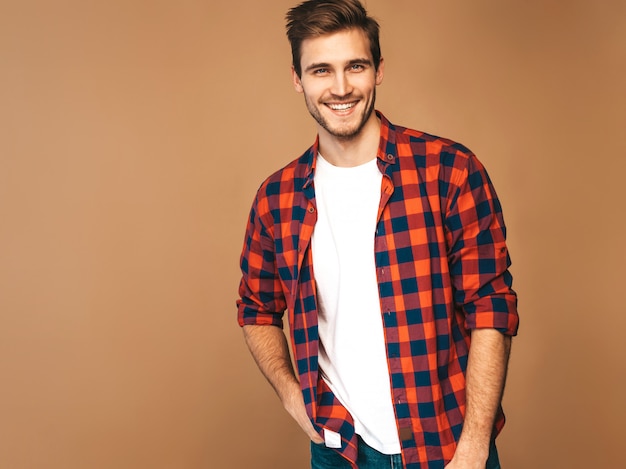 Retrato do modelo elegante jovem sorridente bonito vestido com camisa quadriculada vermelha. homem moda, posar