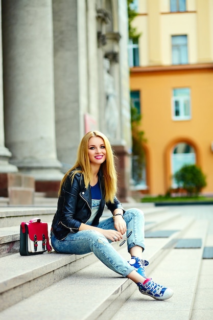 retrato do modelo engraçado engraçado moderno sexy urbano menina mulher jovem e bonita elegante pano moderno brilhante ao ar livre, sentado na cidade de jeans com saco rosa