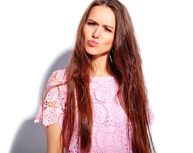 Retrato do modelo moreno de sorriso caucasiano bonito da mulher no vestido à moda do verão cor-de-rosa brilhante isolado no fundo branco. Fazendo uma cara de pato