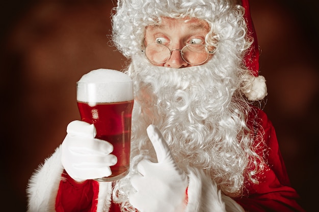 Retrato do papai noel em traje vermelho com uma cerveja