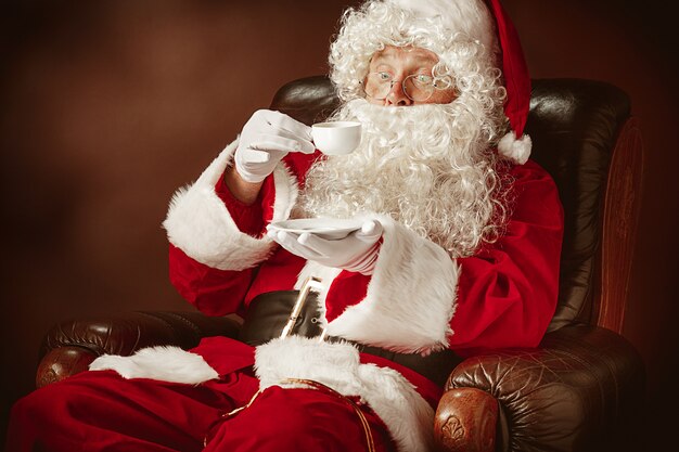 Retrato do Papai Noel em traje vermelho com uma xícara de café