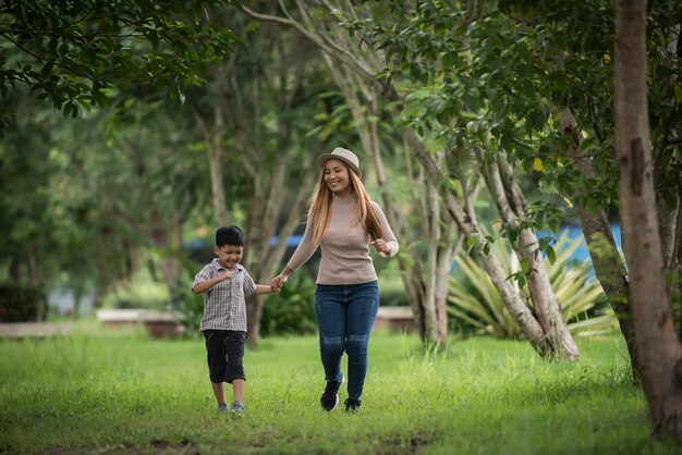 Retrato do passeio feliz da mãe e do filho junto no parque que guarda a mão.