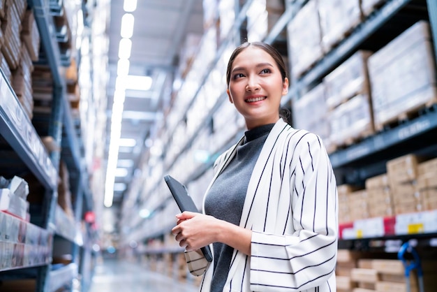 Retrato do proprietário da empresa asiática usando tablet digital, verificando a quantidade de estoque de produtos em estoque na prateleira no armazém de distribuição, serviço de transporte e entrega de negócios logísticos