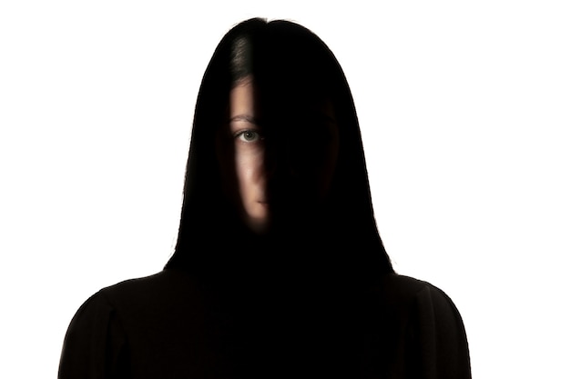 Foto grátis retrato dramático de jovem no escuro, isolado na parede branca do estúdio