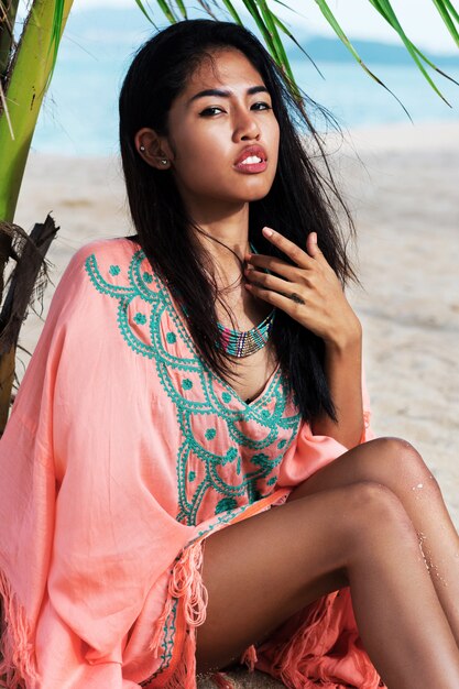 Retrato elegante de mulher asiática posando em uma praia tropical