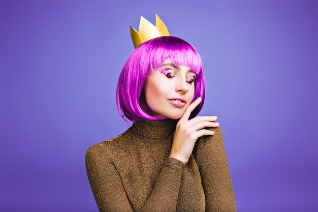 Retrato elegante sensível da jovem alegre elegante comemorando o carnaval na coroa de ouro no espaço violeta.