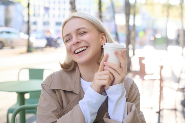 Foto grátis retrato em close-up de uma bela mulher europeia sorridente, feliz, sentada num café e a desfrutar de uma chávena de