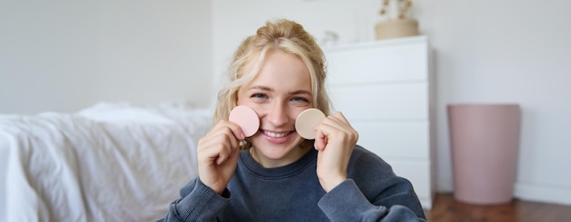 Foto grátis retrato em close-up de uma jovem bonita e feliz mostrando produtos de beleza na câmera recomendando