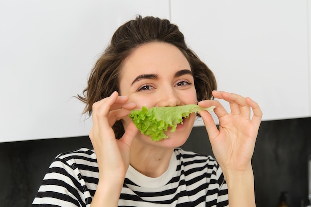 Foto grátis retrato em close-up de uma jovem vegetariana que gosta de comer legumes posando com folhas de alface