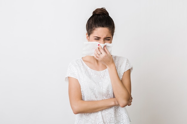 Retrato em close-up de uma mulher bonita assoando o nariz com um guardanapo, resfriada, sentindo-se doente, isolada,, carrancuda