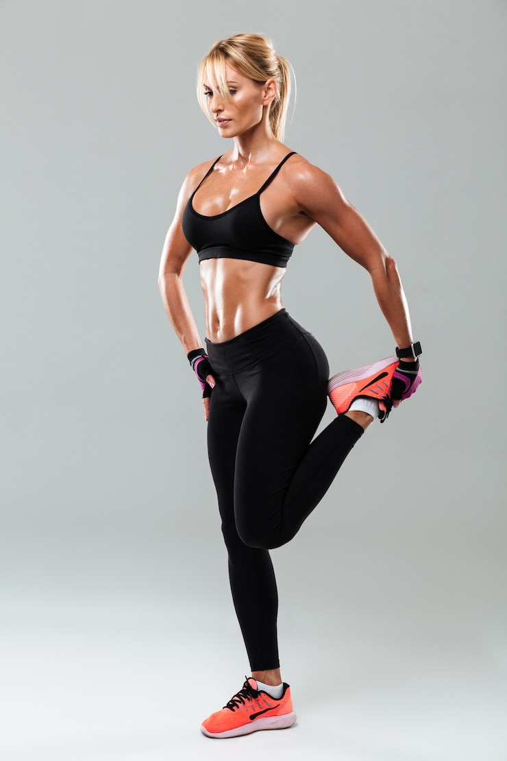 Foto grátis retrato em comprimento de uma bonita desportista fazendo exercícios de alongamento