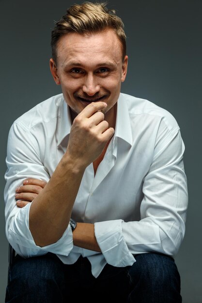 Retrato em estúdio de homem sorridente na camisa branca. Isolado em cinza