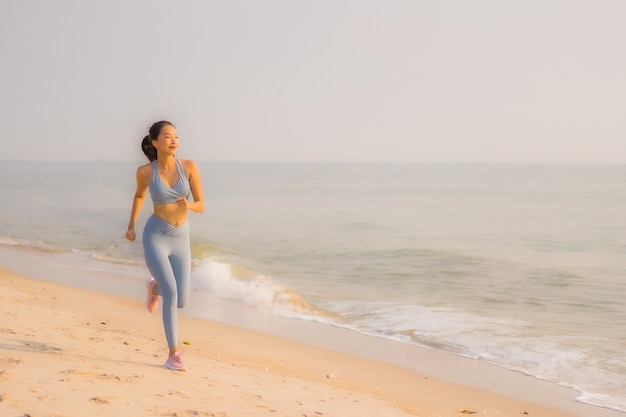 Retrato esporte jovem mulher asiática preparar exercício ou correr na praia mar oceano