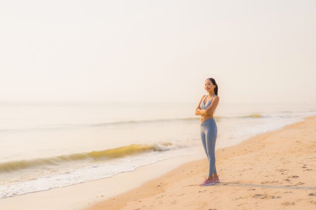 Retrato esporte jovem mulher asiática preparar exercício ou correr na praia mar oceano