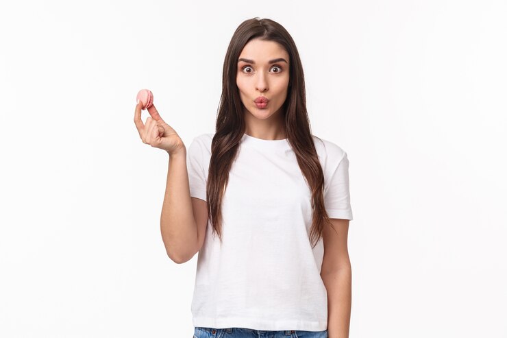 Foto grátis retrato expressivo jovem segurando saborosos dois macarons sobre os olhos
