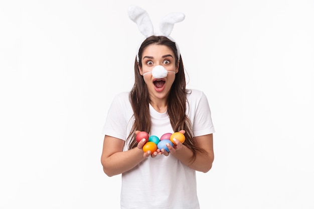 Foto grátis retrato expressivo jovem usando orelhas e nariz de coelho, segurando ovos coloridos