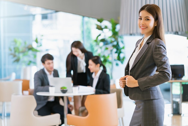 Retrato fecha o sorriso feminino de negócios asiáticos inteligentes e atraentes com confiança e liderança no fundo do escritório moderno