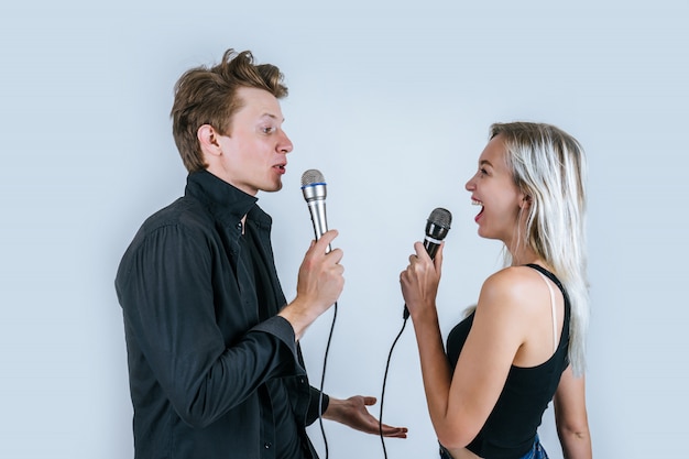 Retrato feliz do casal segurando o microfone e cantar uma canção