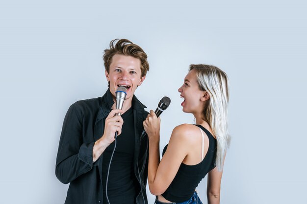 Retrato feliz do casal segurando o microfone e cantar uma canção