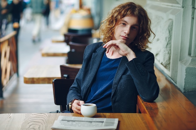 Retrato hipster homem avermelhado com café e jornal