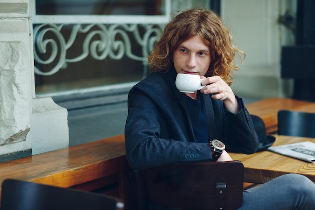 Retrato homem avermelhado interessante posando com café