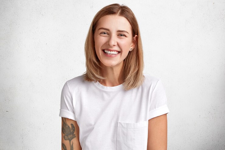 Foto grátis retrato horizontal de mulher feliz tem uma expressão alegre, vestida com uma camiseta branca casual, expressa positividade, sendo feliz em passar o tempo livre com o namorado.