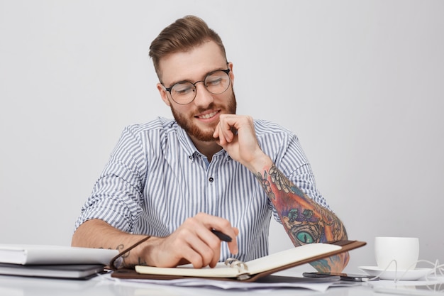 Foto grátis retrato horizontal de um empresário tatuado com um sorriso no rosto, feliz por ter muitos dias livres