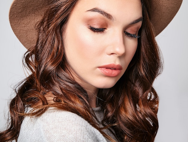 Retrato horizontal do modelo feminino atraente e elegante usa roupas de verão e chapéu marrom com maquiagem natural
