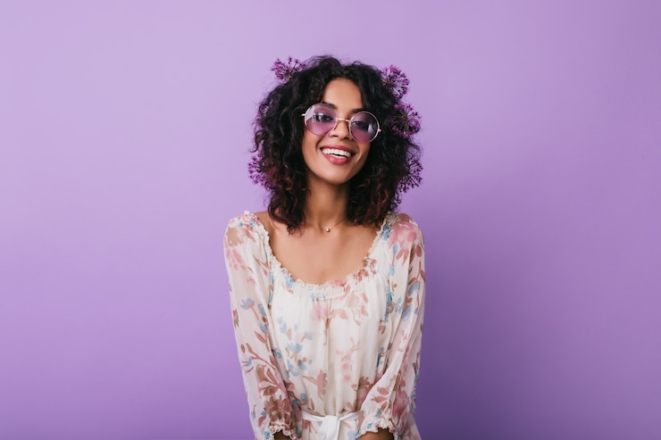 Foto grátis retrato interior de mulher bronzeada alegre com flores no cabelo. feliz modelo feminino africano isolado.