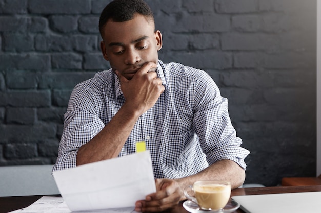 Retrato interno de um homem de negócios sério e bonito, de pele escura, com camisa quadriculada formal