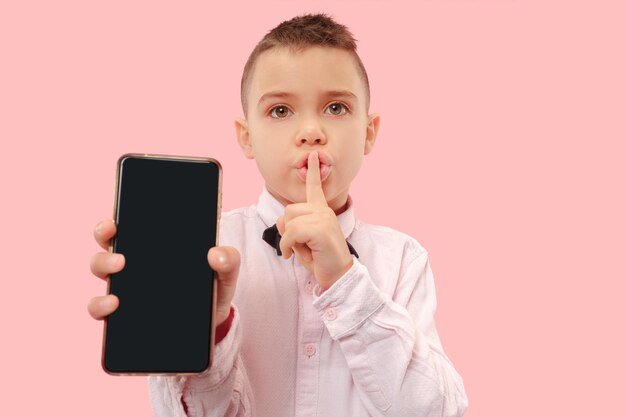 Retrato interno de um jovem atraente segurando um smartphone em branco