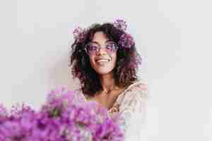 Foto grátis retrato interno de uma garota negra despreocupada, olhando para longe durante a sessão de fotos com flores. mulher africana satisfeita, expressando interesse enquanto posava com alliums.