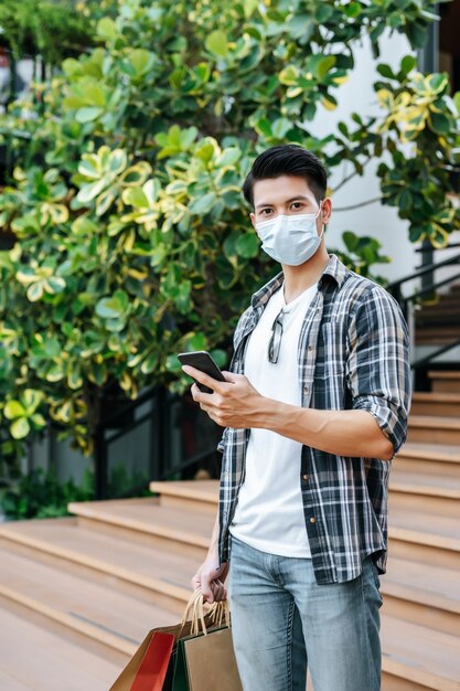 Retrato Jovem bonito com máscara de proteção segurando um saco de papel