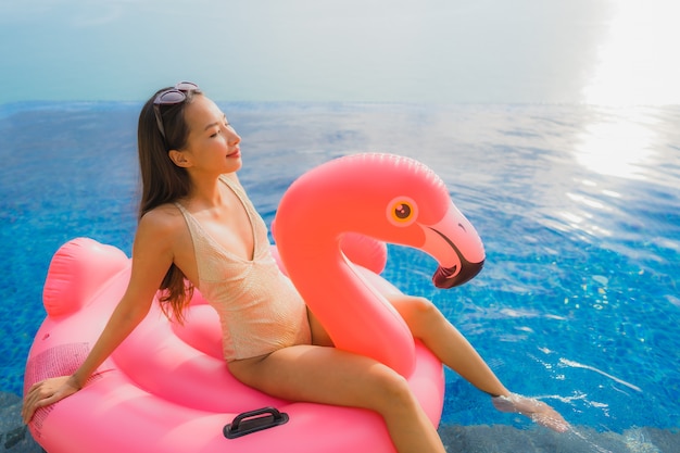 Retrato, jovem, mulher asian, ligado, inflável, float, flamingo, ao redor, piscina ao ar livre, em, hotel, recurso