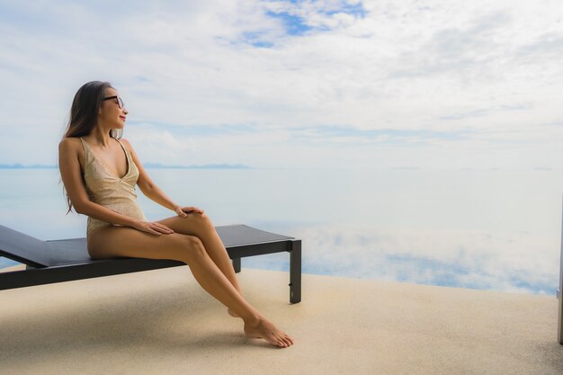 Retrato jovem mulher asiática relaxar sorriso feliz ao redor da piscina no hotel e resort