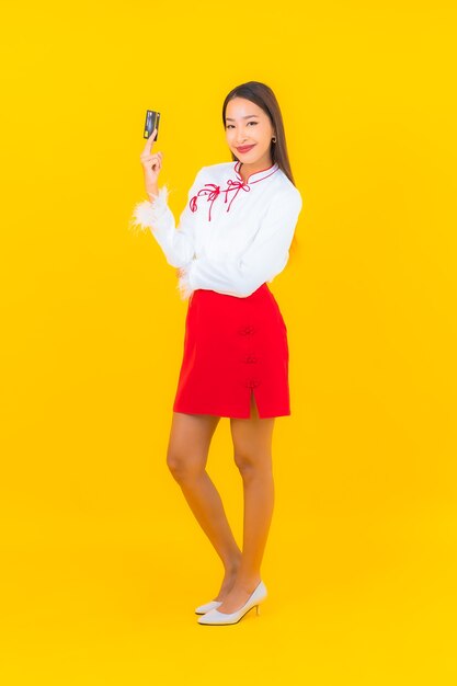 Retrato linda jovem asiática com cartão de crédito para compras online em amarelo