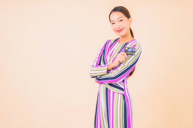 Retrato linda jovem asiática com celular inteligente e cartão de crédito em cores.