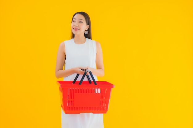 Retrato linda jovem asiática com cesta de compras para fazer compras no supermercado