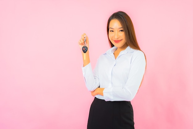 Retrato linda jovem asiática com chave do carro na parede rosa isolada