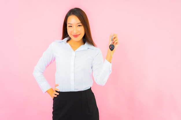 Retrato linda jovem asiática com chave do carro na parede rosa isolada