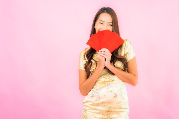 Retrato linda jovem asiática com envelopes vermelhos na parede rosa