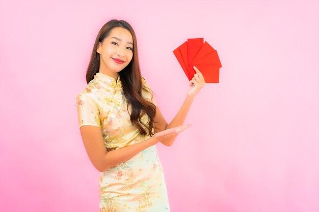 Retrato linda jovem asiática com envelopes vermelhos na parede rosa