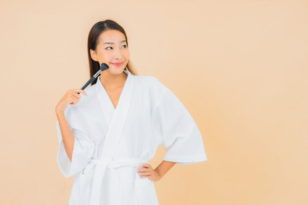 Retrato linda jovem asiática com pincel de maquiagem bege